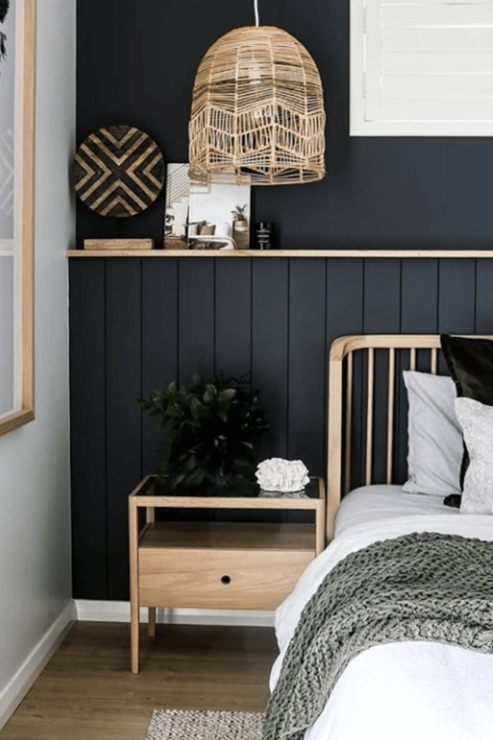 black half wall shiplap panelling with wooden shelf and black upper half, there is a wooden bed frame and bedside table in front of it